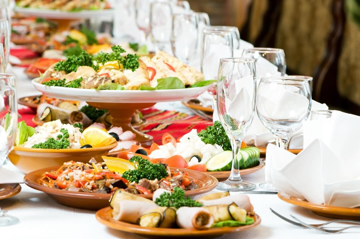 Hvitdekket bord med fat av tapas, vinglass og brettede servietter klart til servering